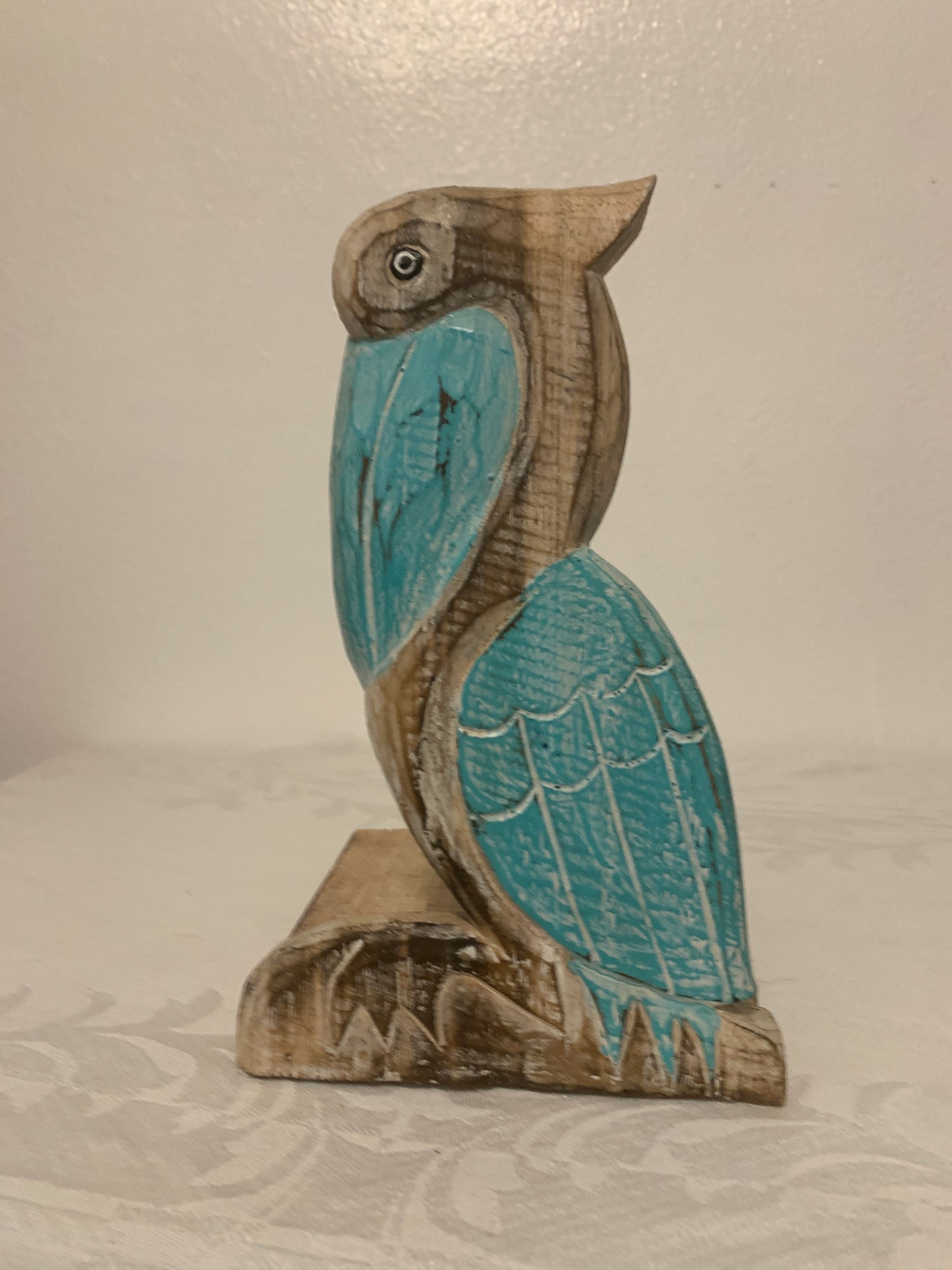 Decorative pelican-shaped object with blue and brown colors on a neutral background