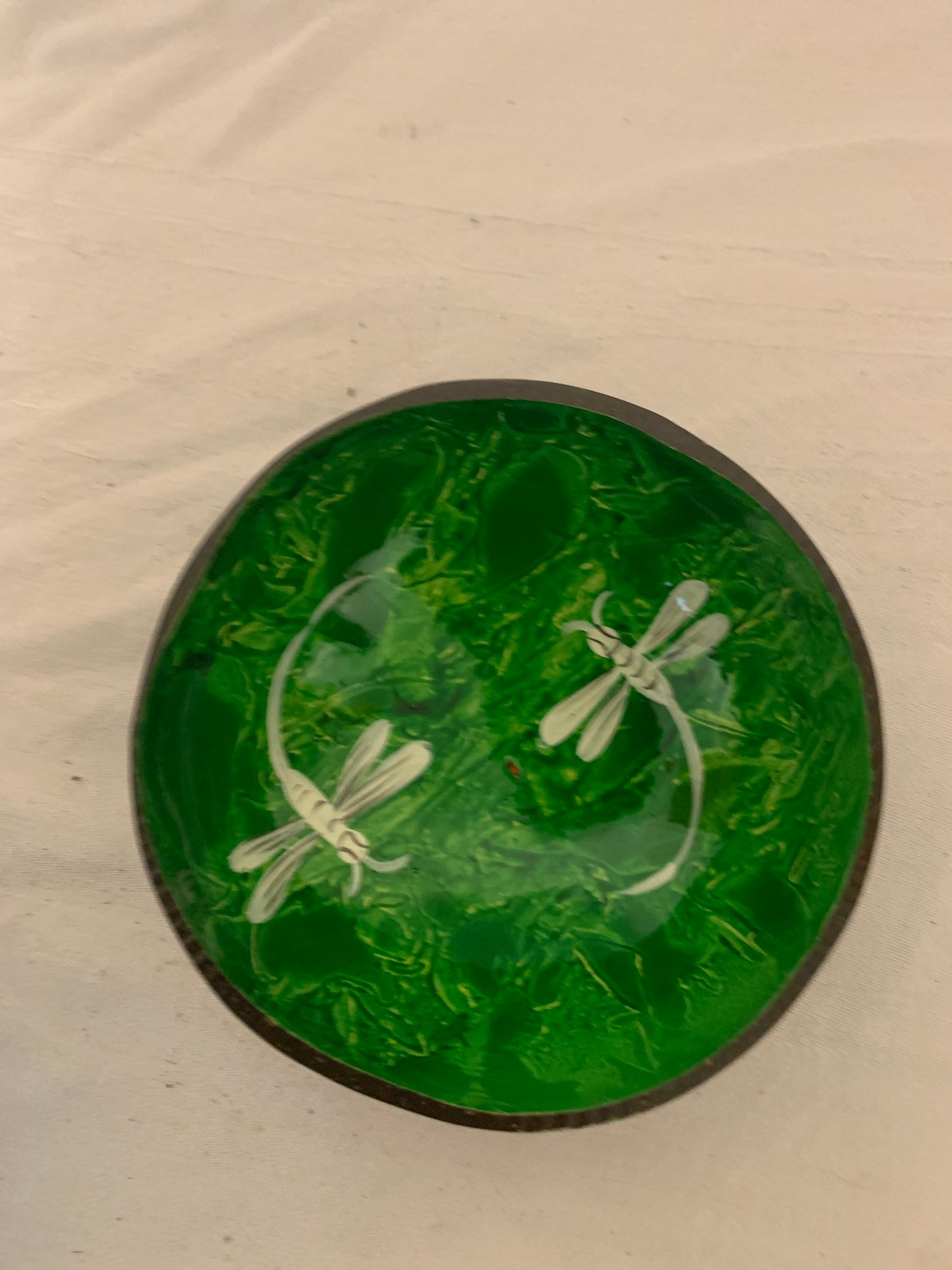 Green glass plate with white dragonfly design on a beige background