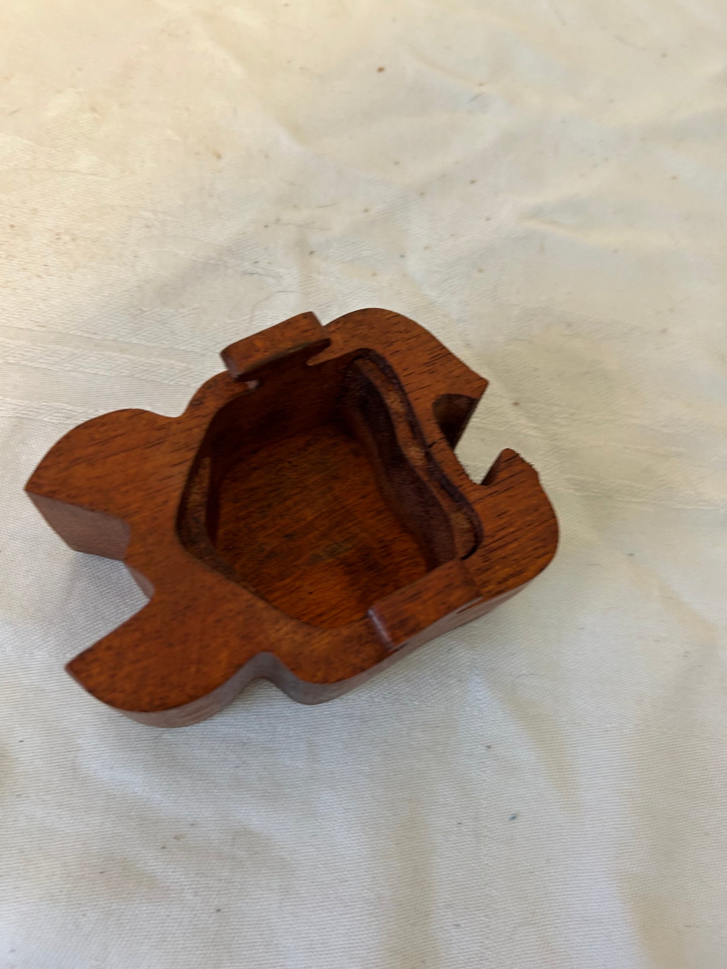 Wooden Turtle-shaped object on a white fabric background