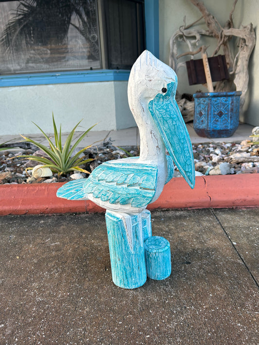 Blue ceramic bird sculpture on a concrete surface with a plant and decorative items in the background.