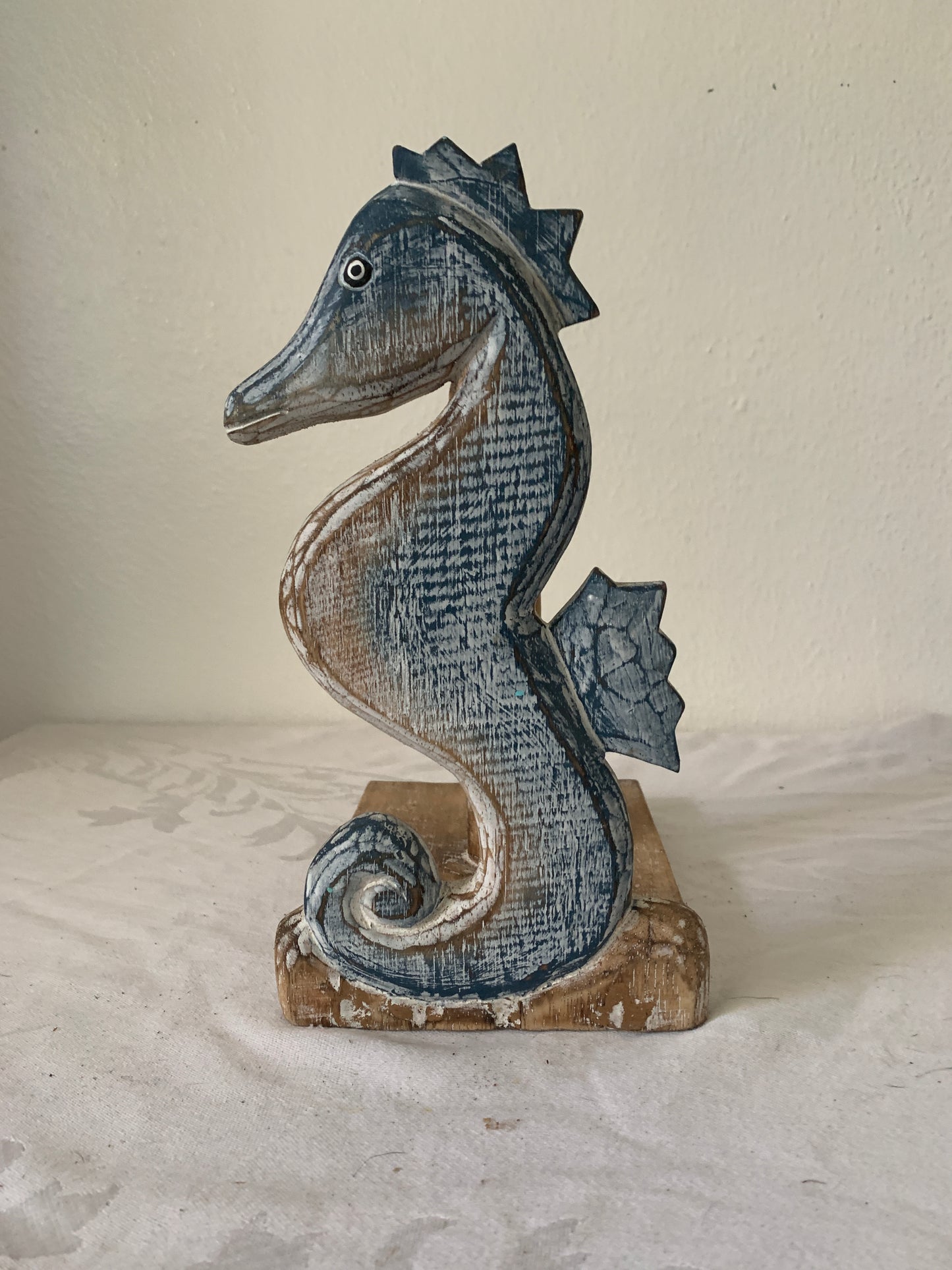 Decorative wooden seahorse sculpture on a textured wall